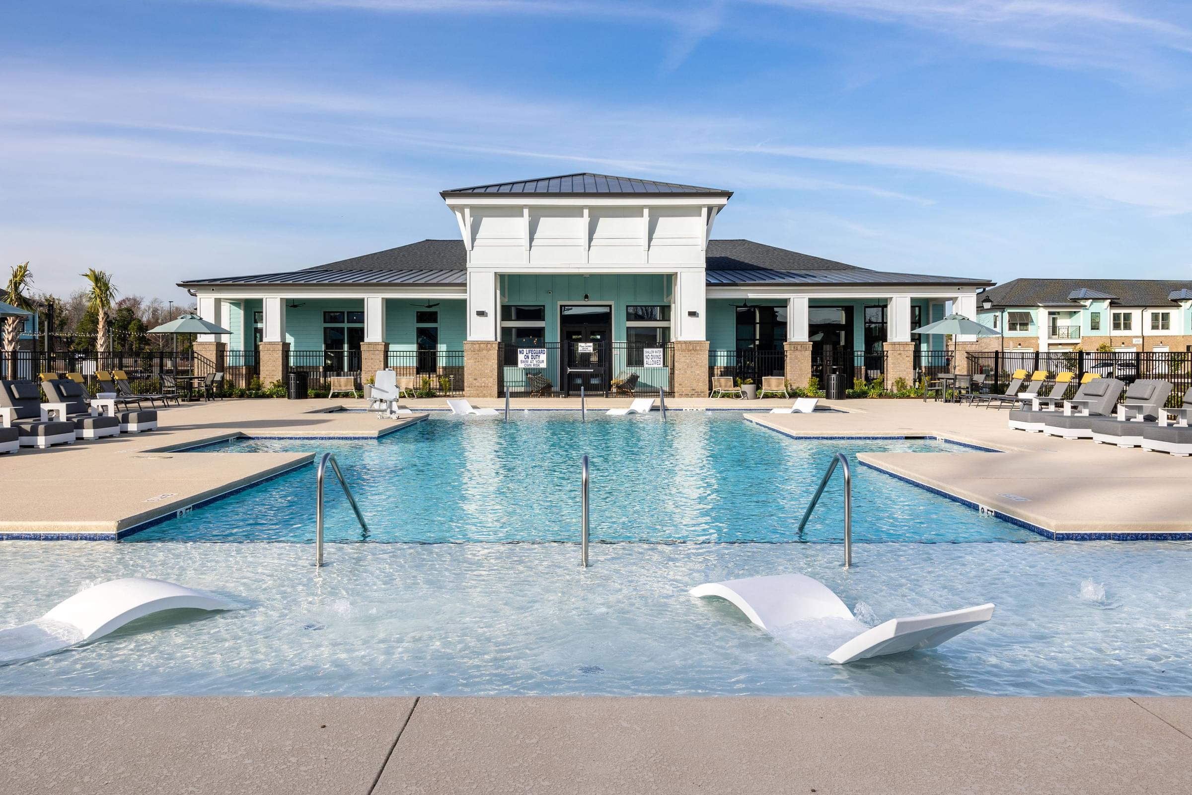 a swimming pool with chairs and a building in the background