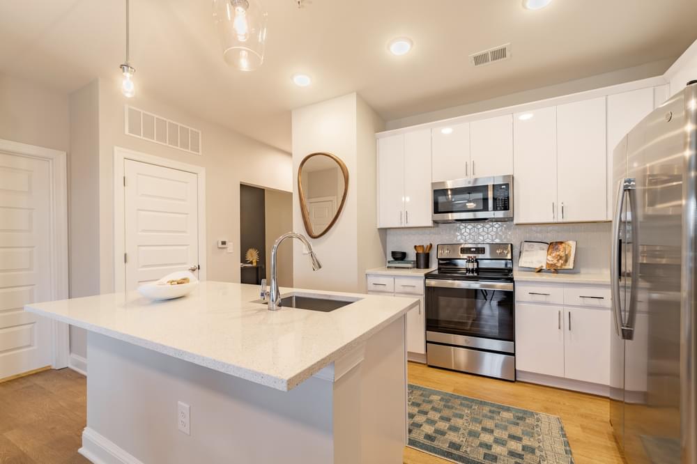 a white kitchen with stainless steel appliances and a white counter top
