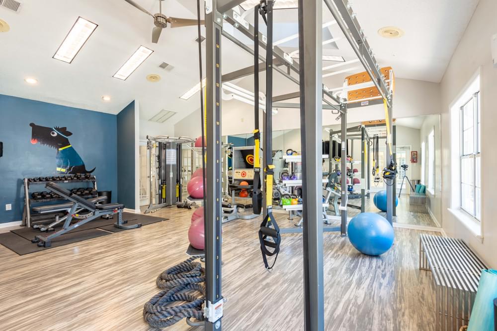 a spacious fitness room with exercise equipment and a large window