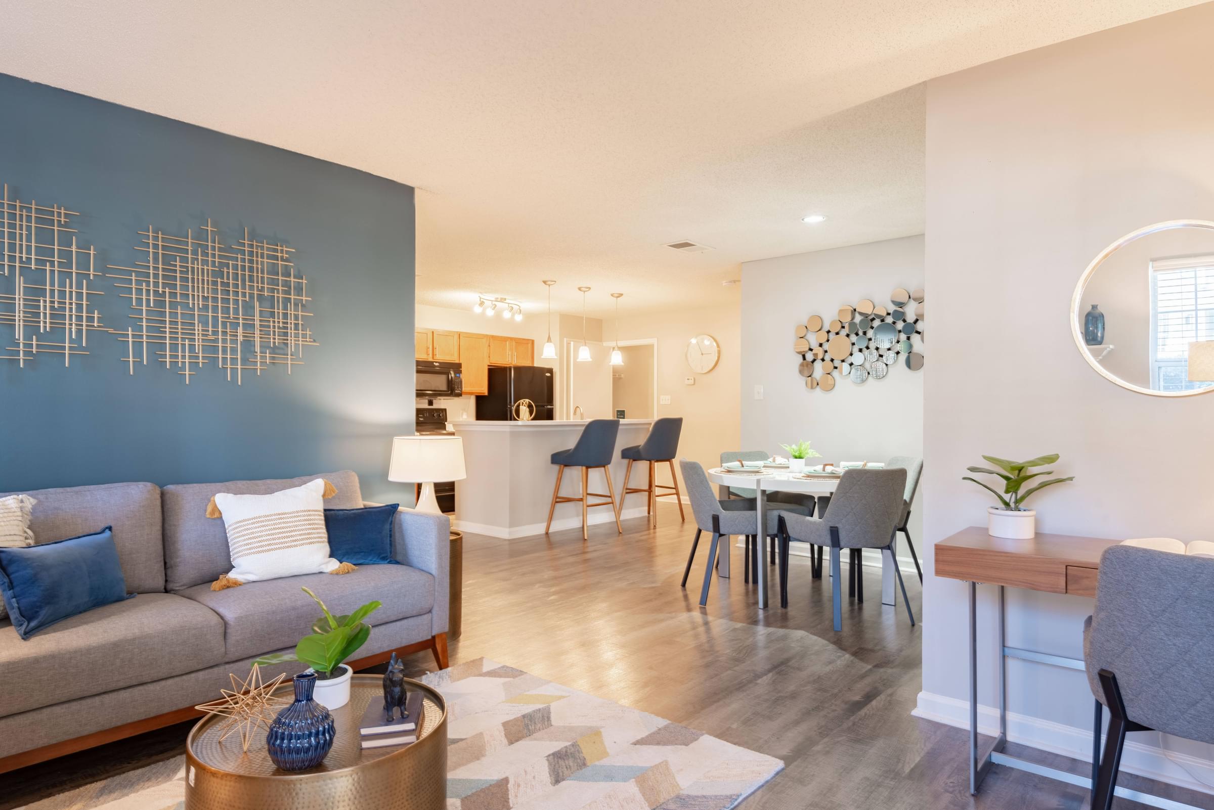 a living and dining room area with a couch table and chairs and a kitchen in the background
