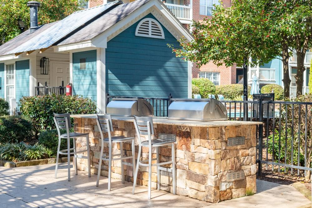 a large outdoor kitchen with a bar and stools in front of a blue house