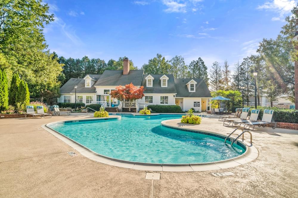 a pool with chairs and a house in the background