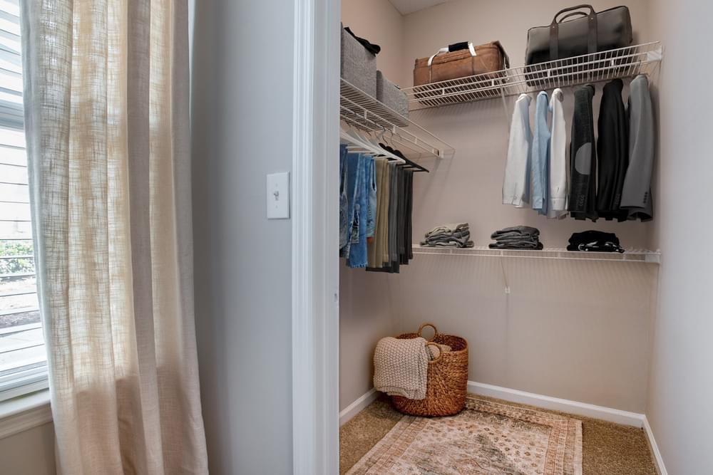 a closet with shelves and a window with clothes hanging on it