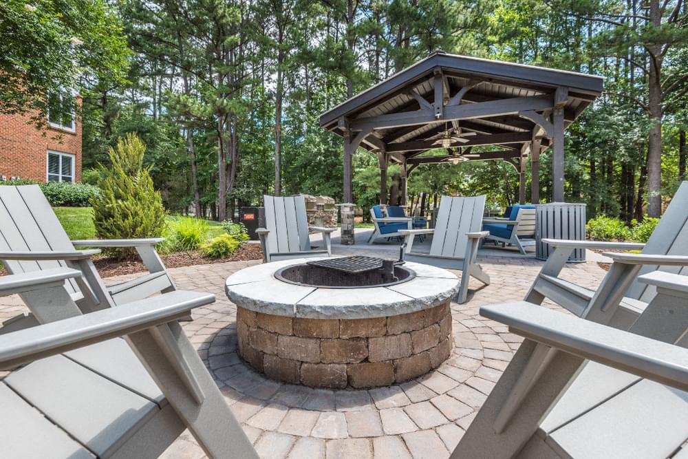 a fire pit with chairs around it and a pavilion