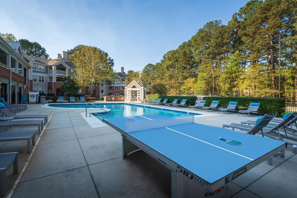 a pool with a ping pong table and lounge chairs around it