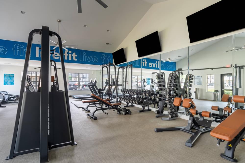a spacious fitness center with cardio equipment and large windows