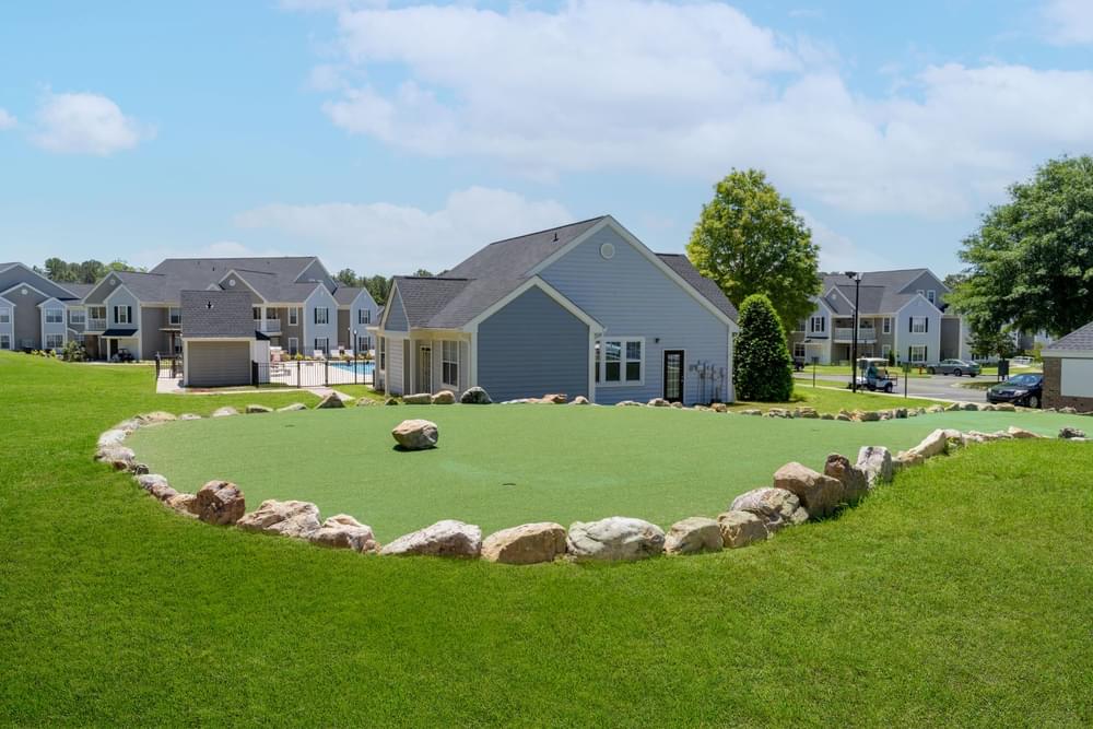 a circle of rocks on a green lawn in front of a house