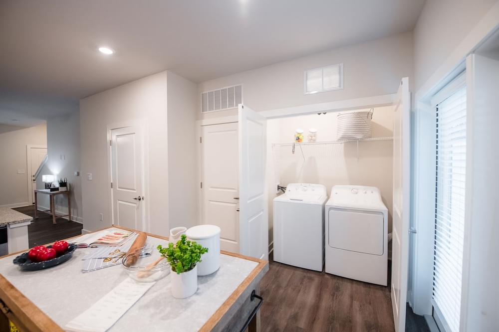a kitchen with a washer and dryer and a table with a plant on it