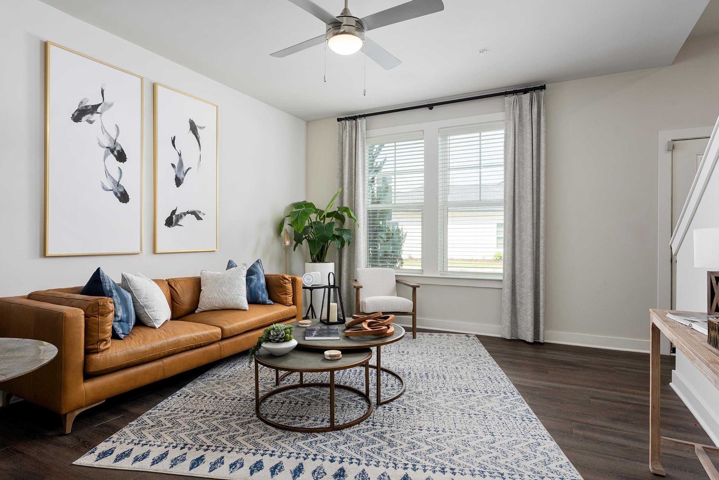 A living room with a brown sofa, a coffee table, and a ceiling fan.
