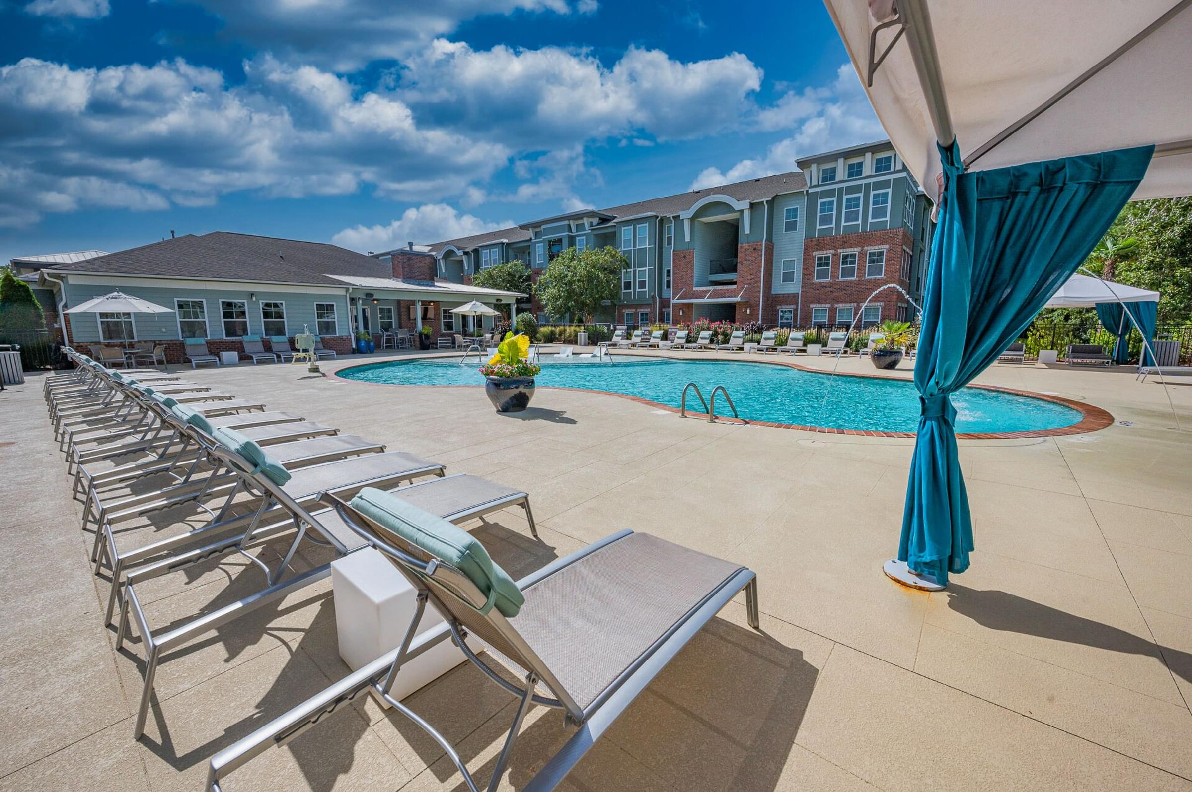 A pool area with sun loungers and a blue umbrella