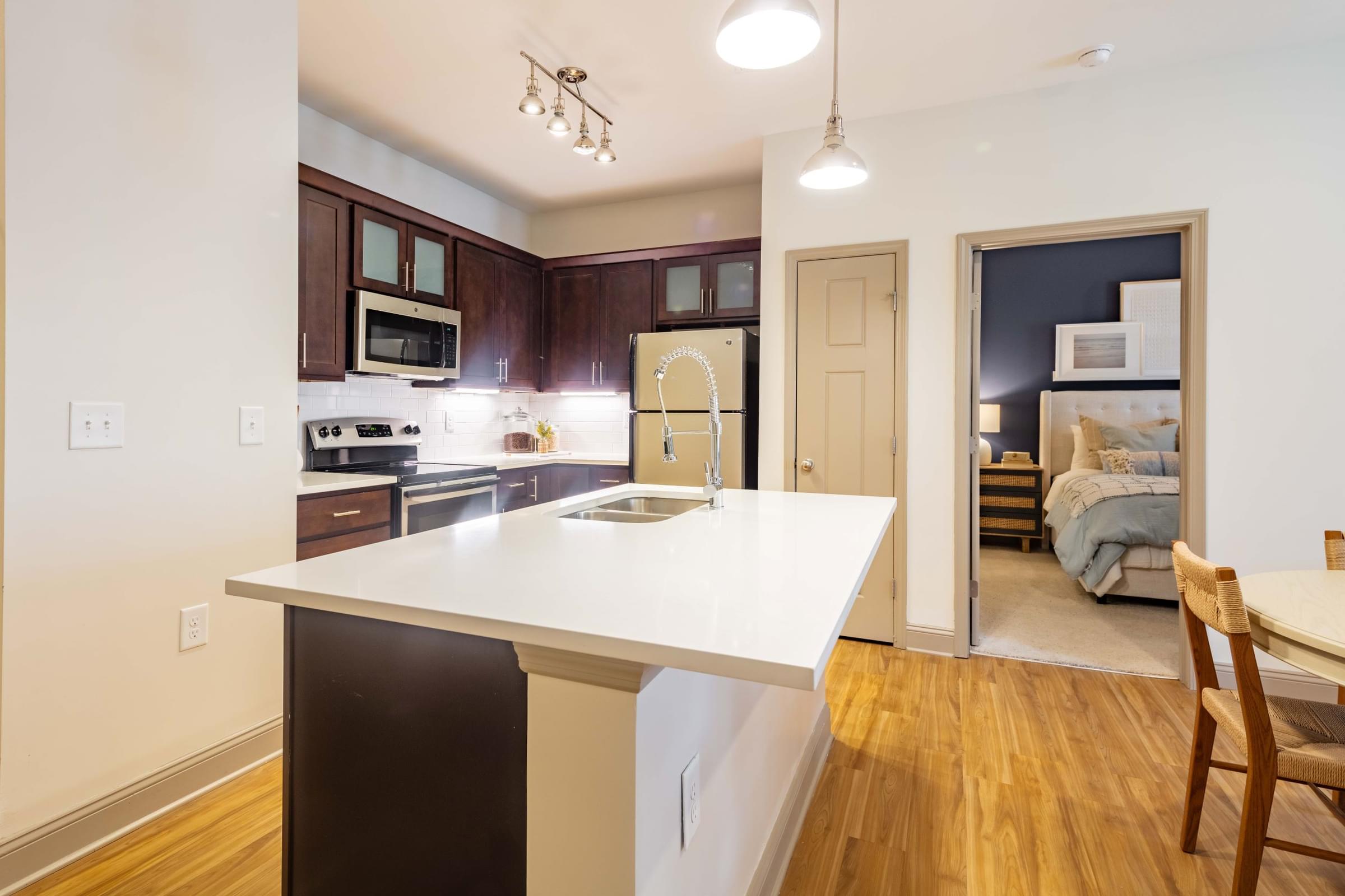 A kitchen with a white counter top and wooden floors