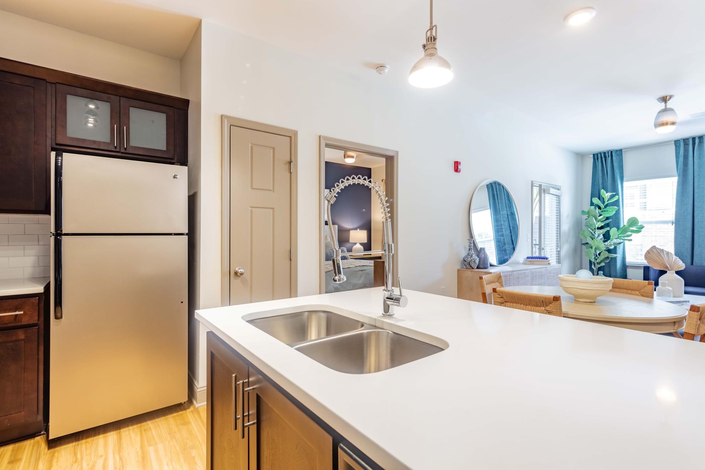 A kitchen with a refrigerator, sink, and wooden cabinets