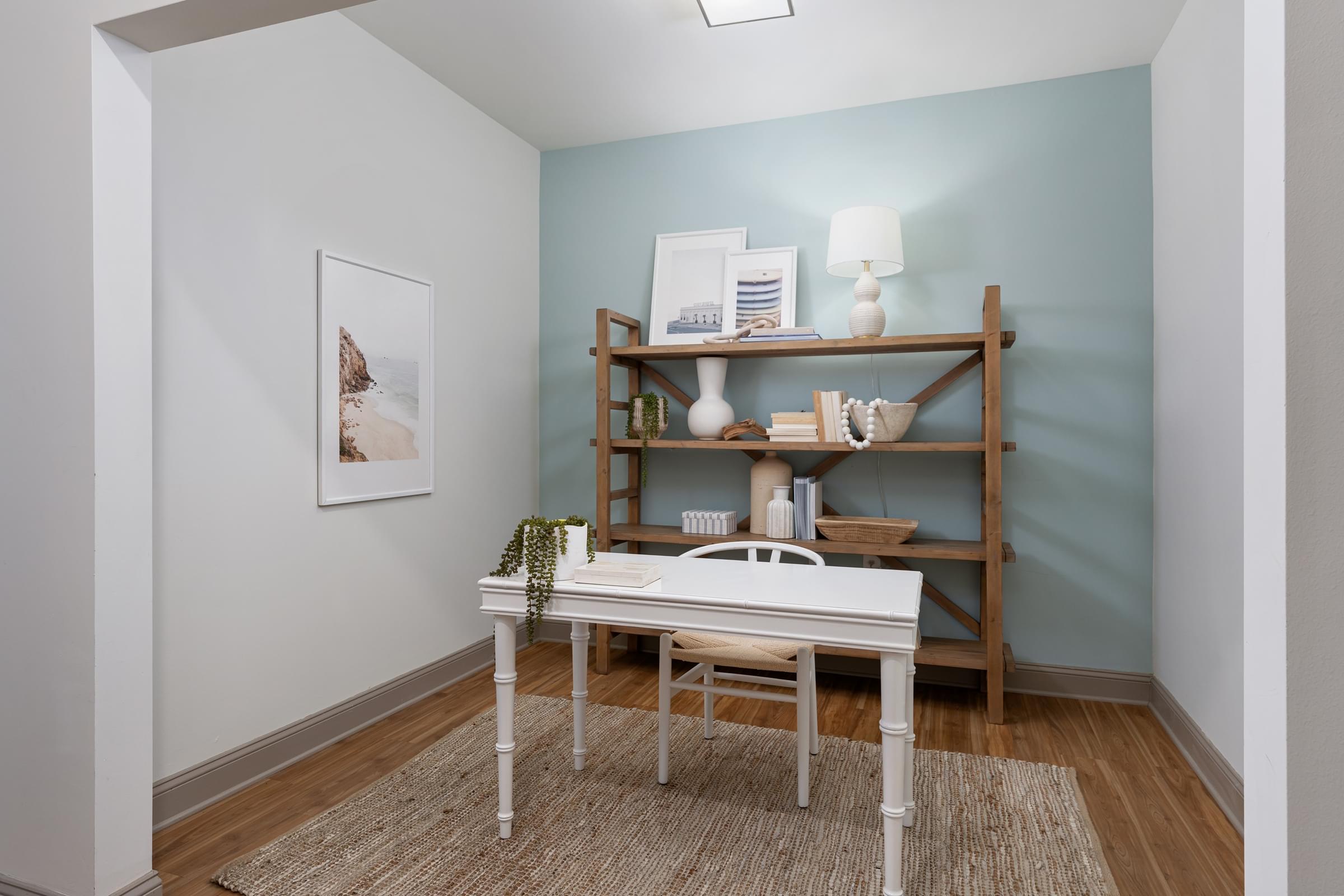 A white table with a plant on it sits in front of a blue wall.