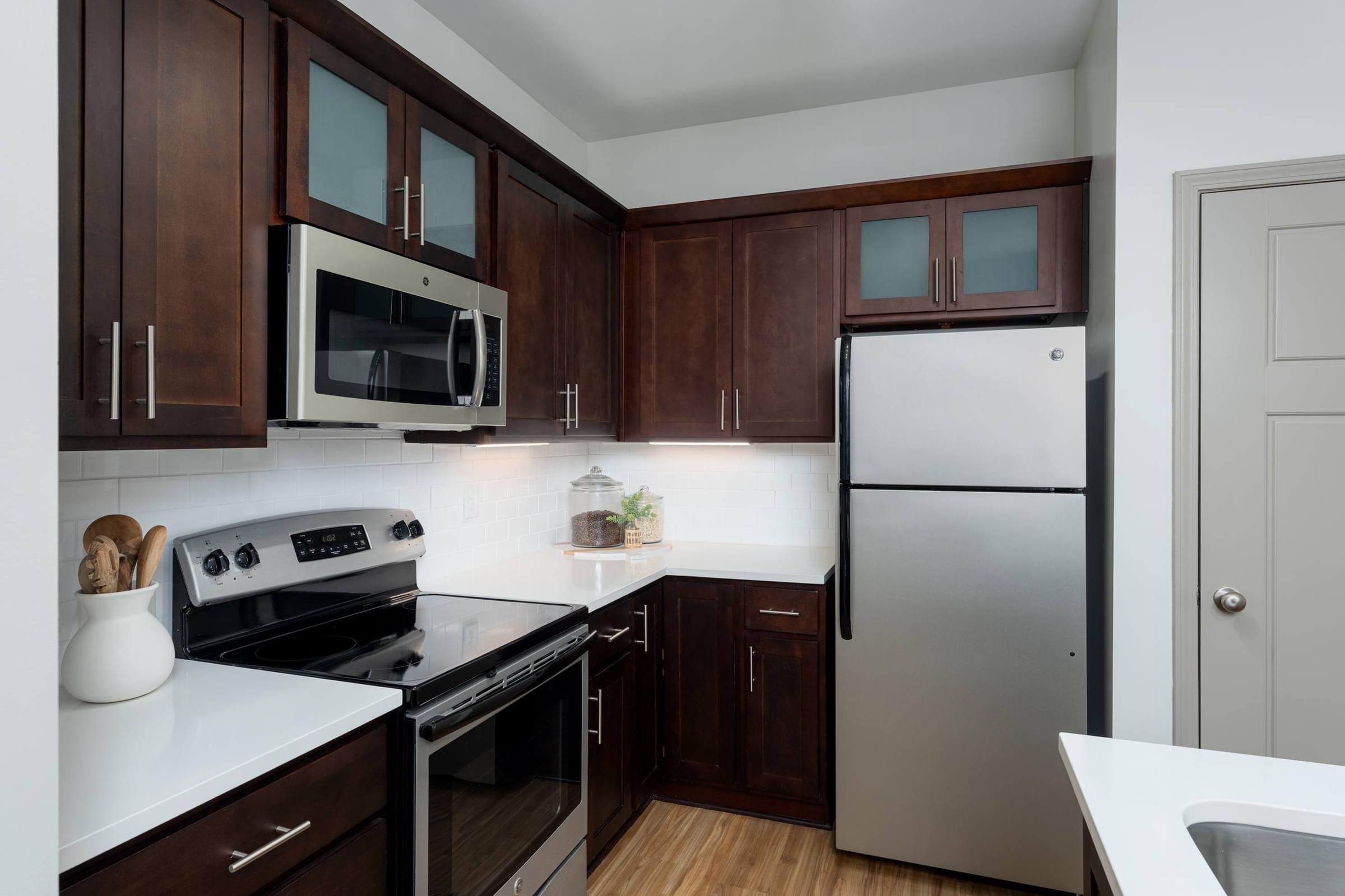 A kitchen with dark wood cabinets and stainless steel appliances.