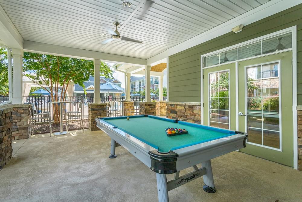 a pool table in the patio of a house with a porch