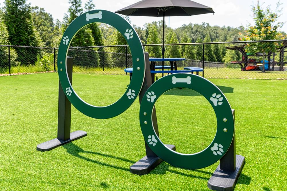 a large green horseshoe is in the middle of a grassy area with an umbrella