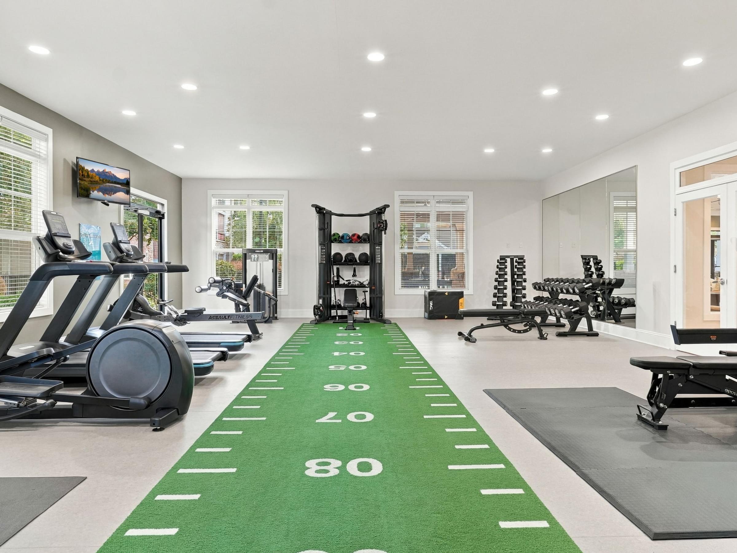 A gym with a green running track and exercise equipment.