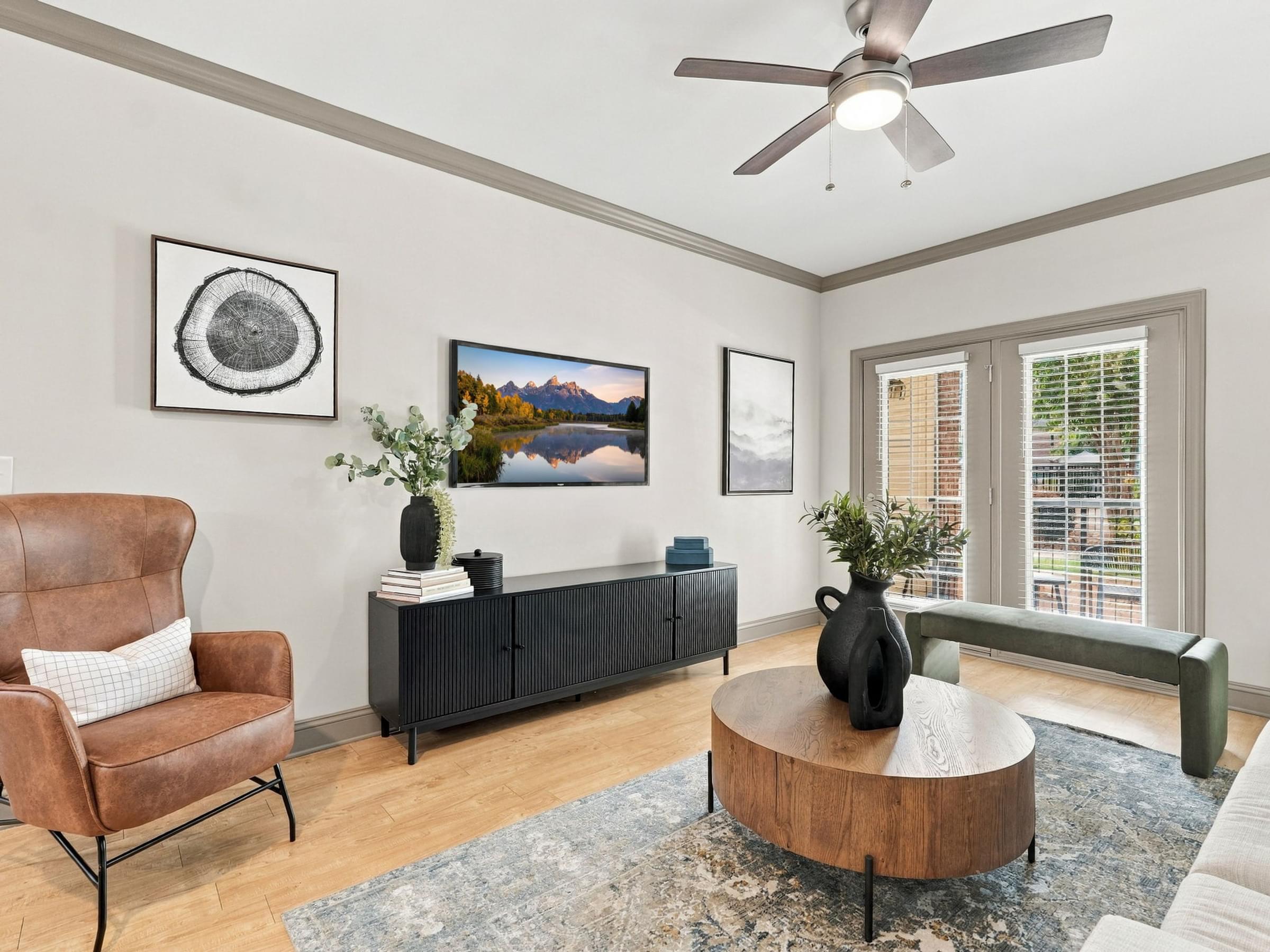 A living room with a brown leather chair, a wooden coffee table, and a painting of a mountain landscape on the wall.