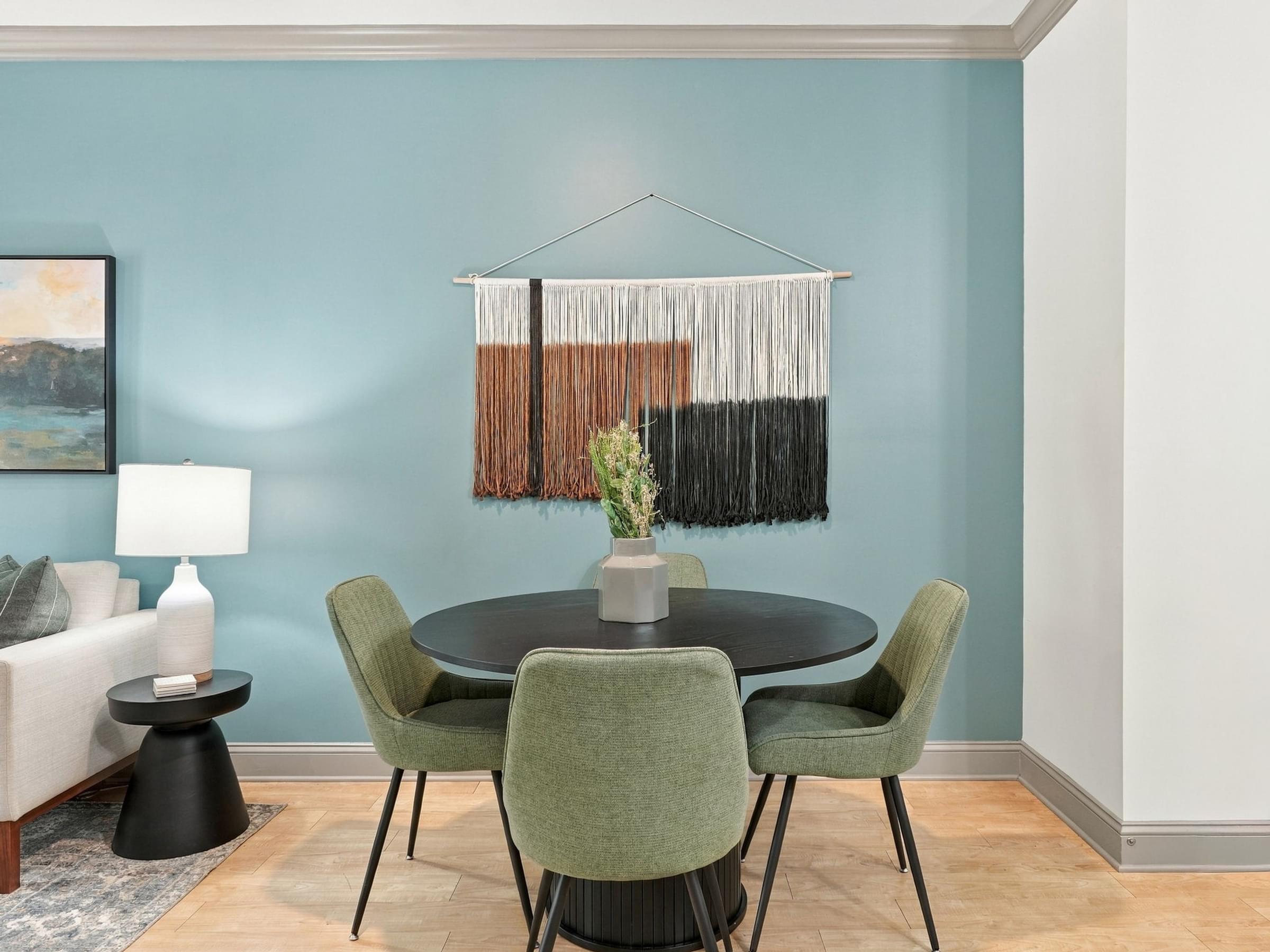 A dining room with a round table and green chairs.