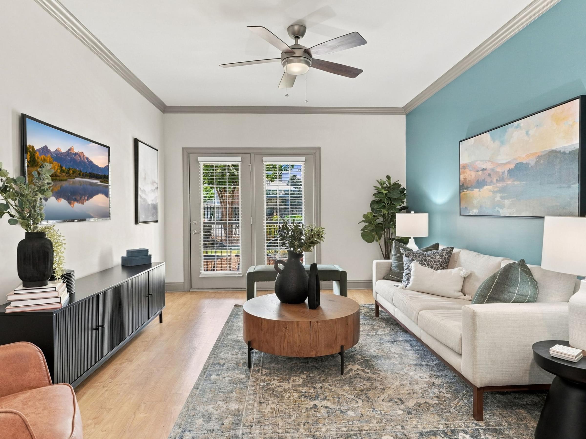 A living room with a ceiling fan, a sofa, a coffee table, and a painting on the wall.