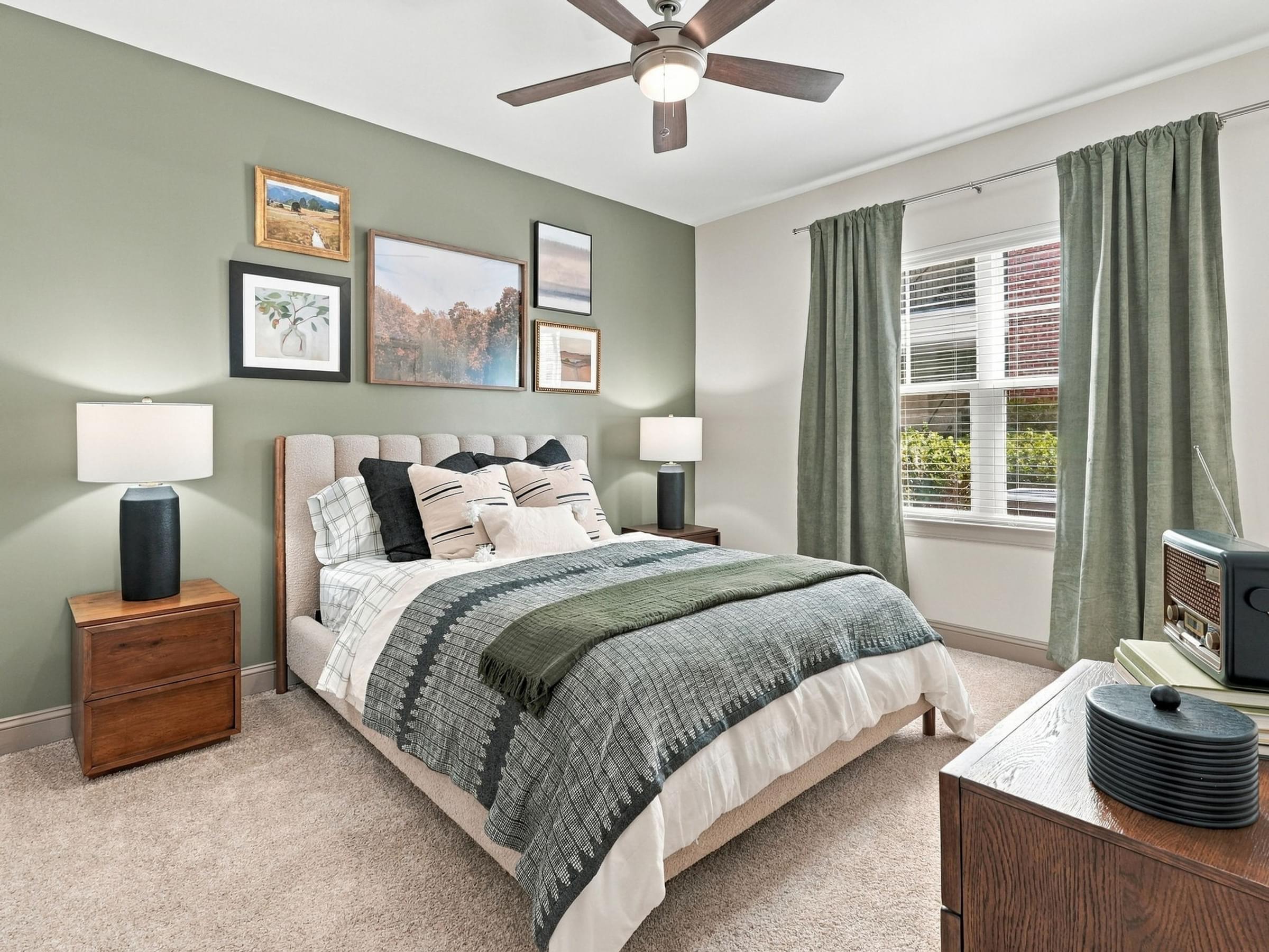 A bedroom with a bed, nightstand, and a ceiling fan.