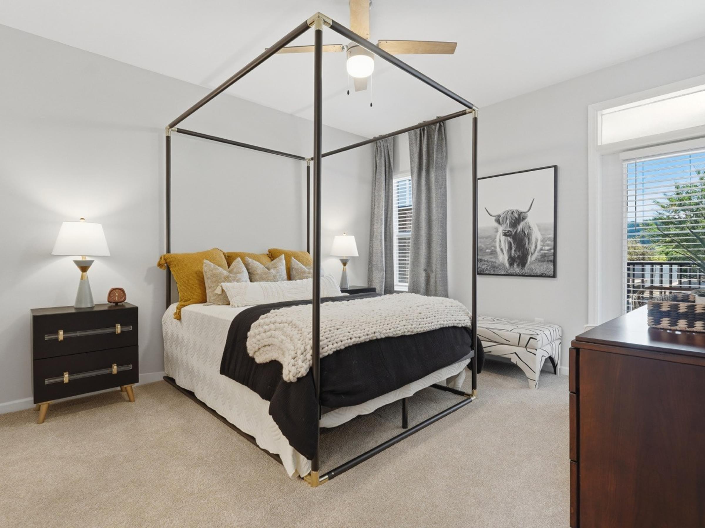 A bedroom with a four poster bed and a painting of a cow on the wall.
