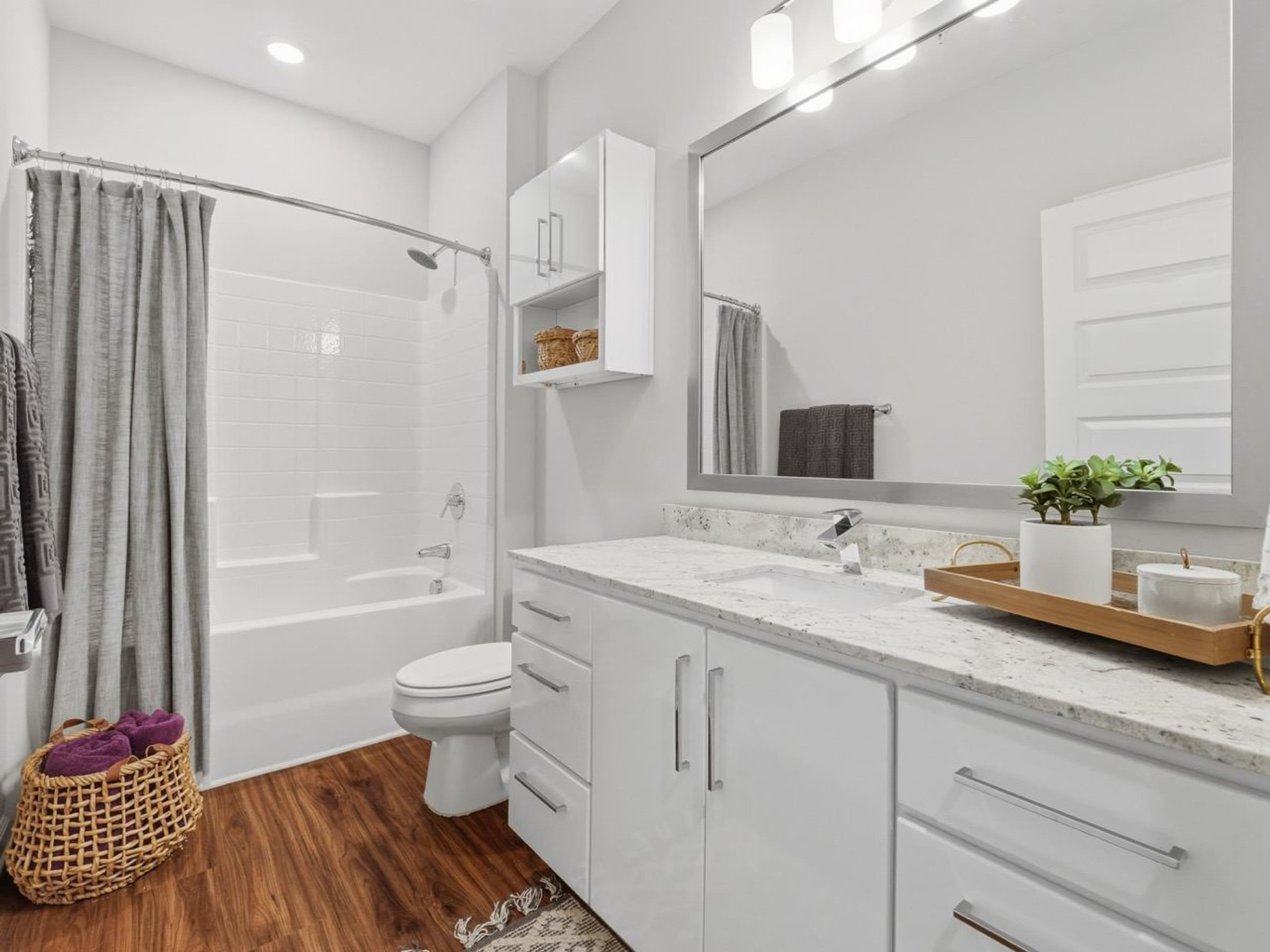 A white bathroom with a wooden floor and a white toilet.