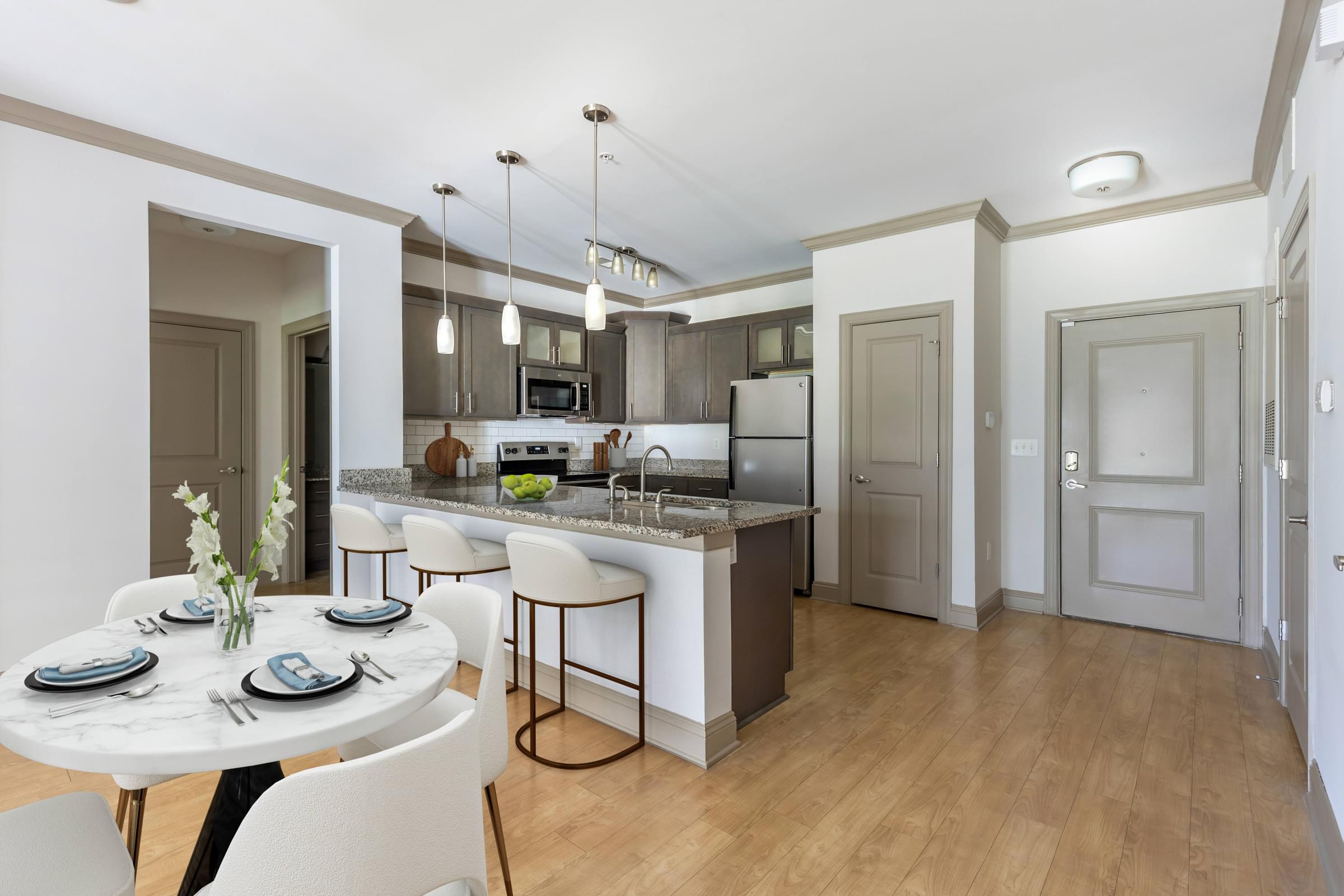 A modern kitchen with a dining table set for two.