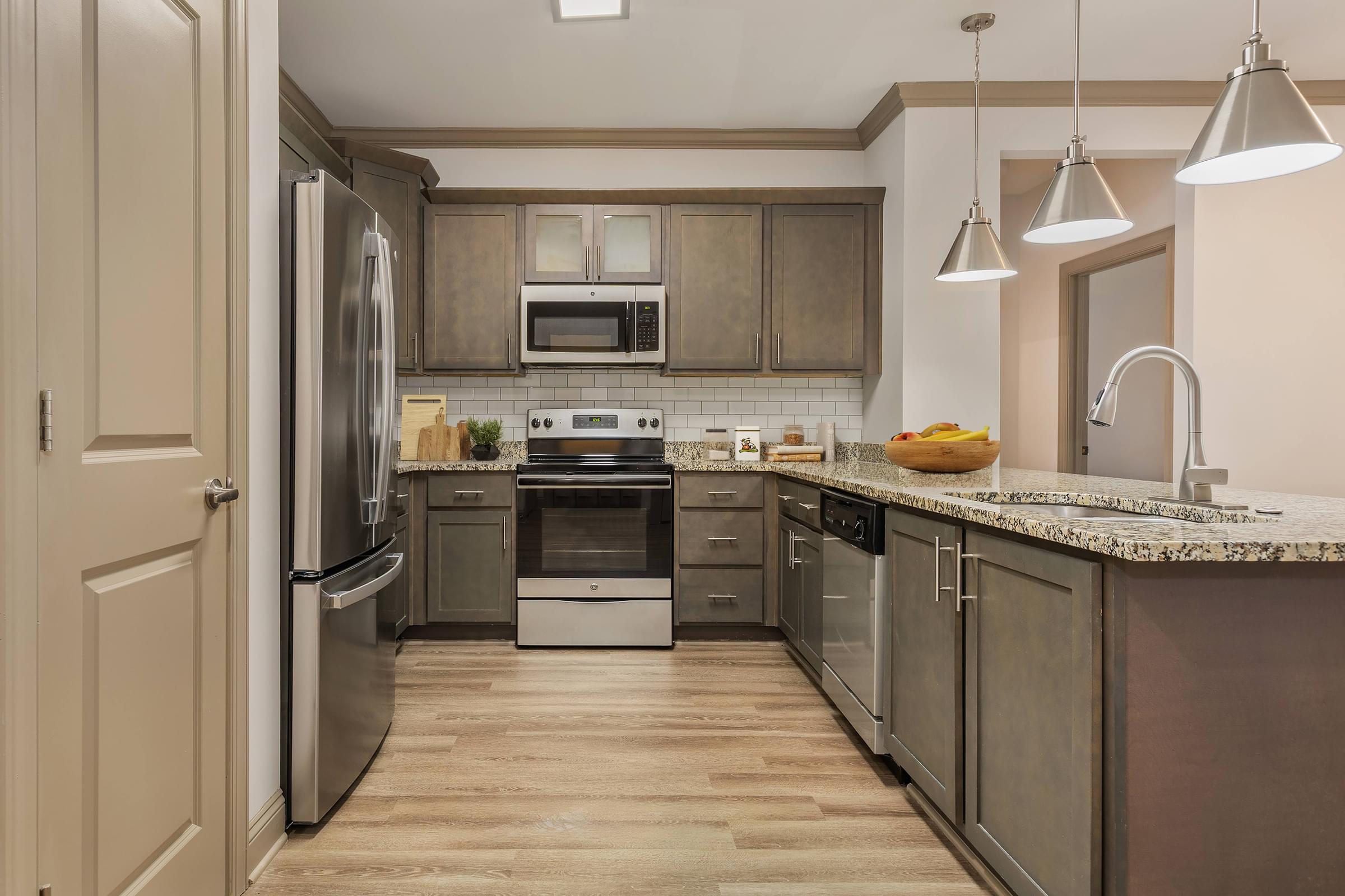 A kitchen with a refrigerator, oven, and sink.