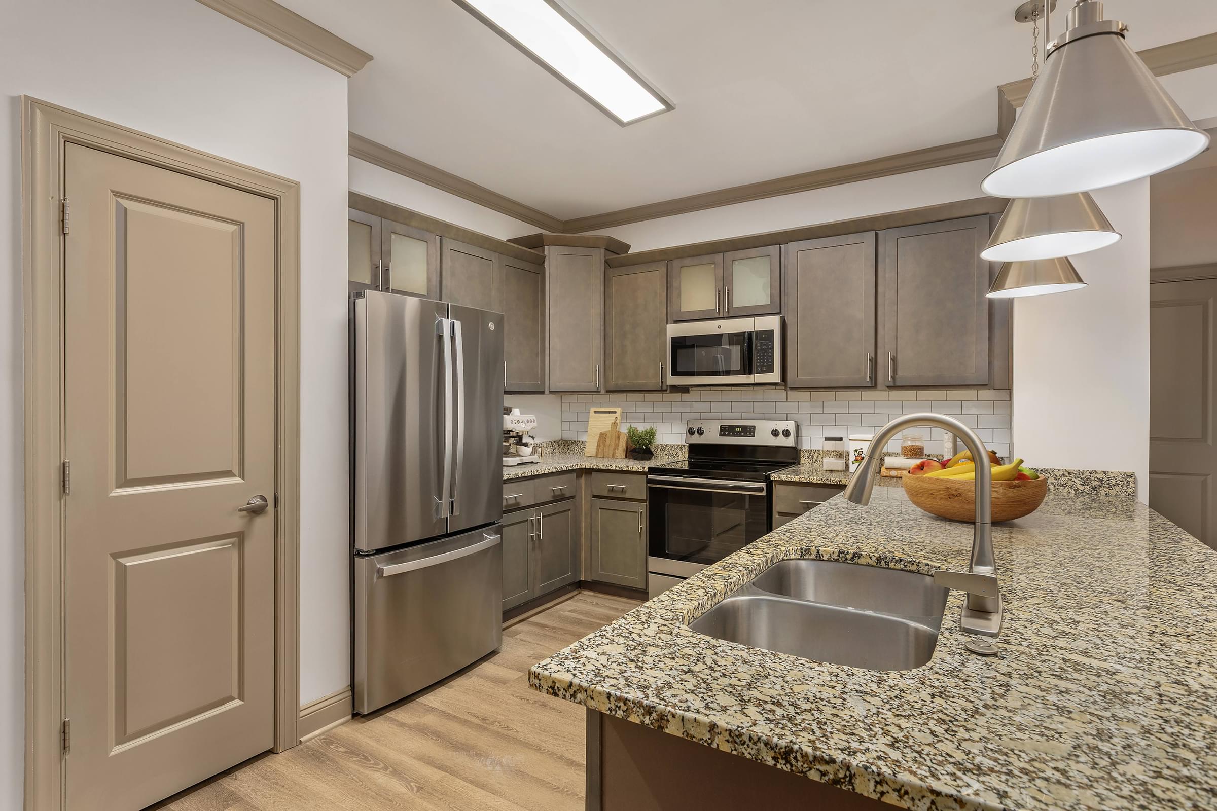 A kitchen with a granite countertop and stainless steel appliances.