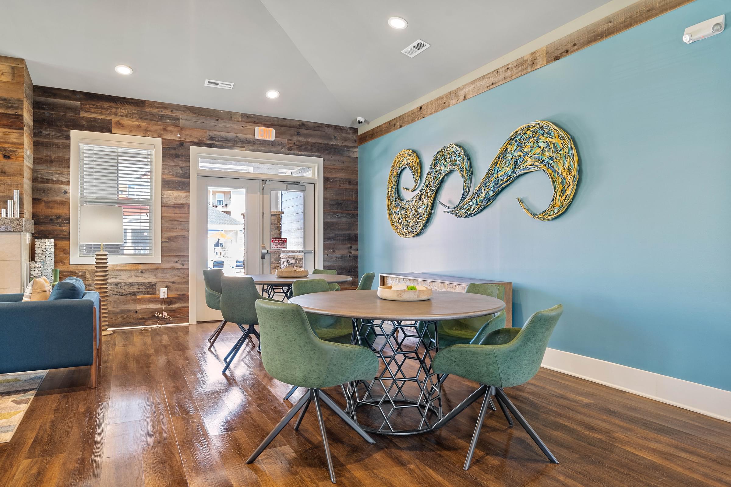 a dining room with a table and chairs and a blue wall with an abstract painting