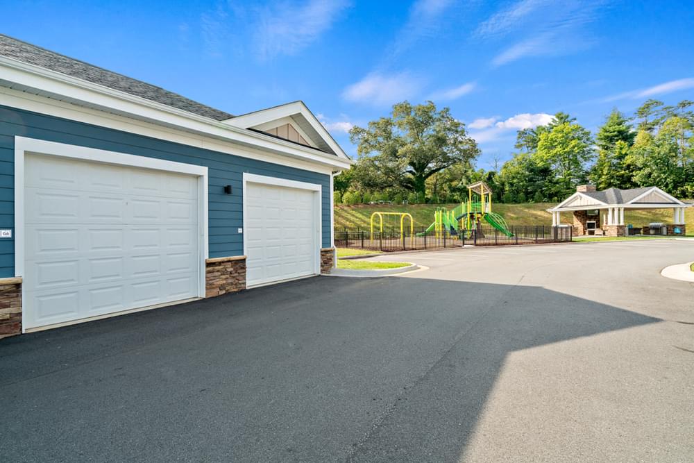 a garage with two white garage doors and a playground in the background