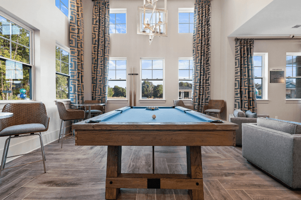 a games room with a pool table in the center of a room with windows