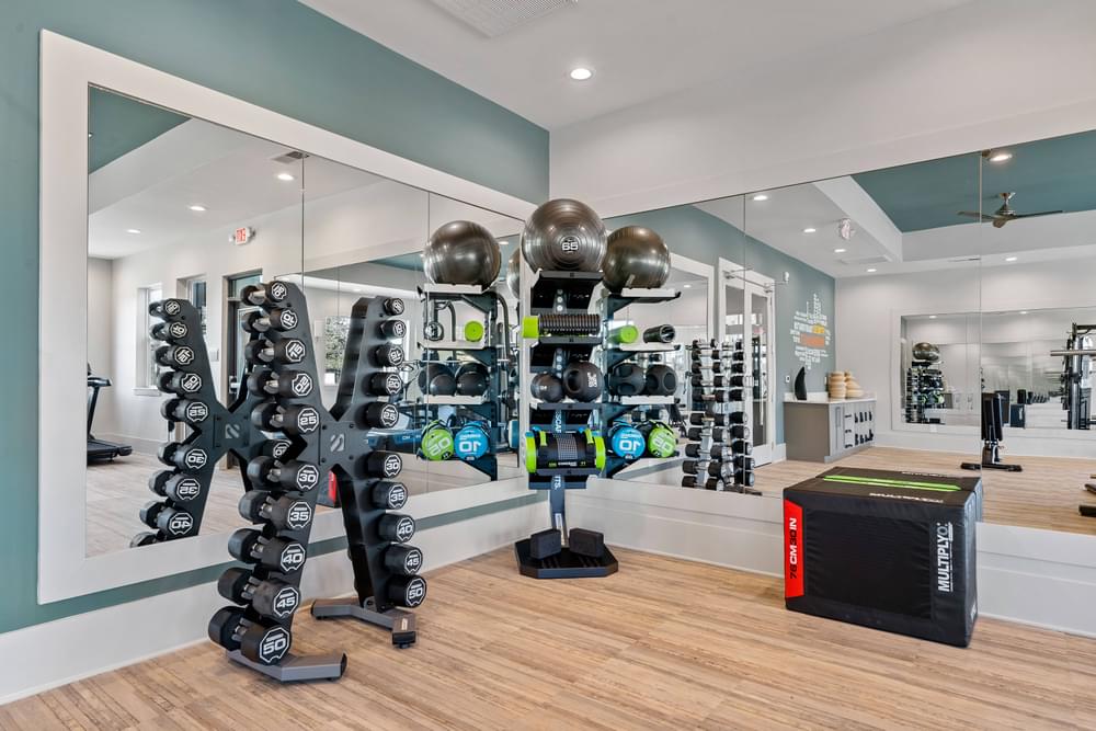 the home gym has a large mirror and a rack of dumbbells