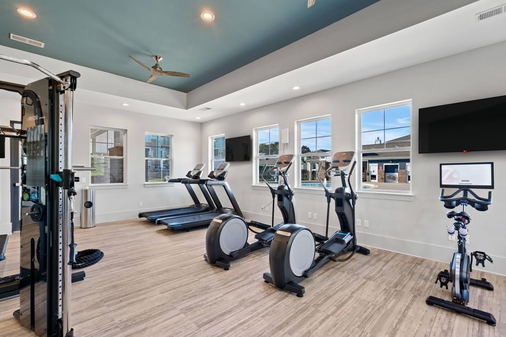 a gym with treadmills and weights and a tv