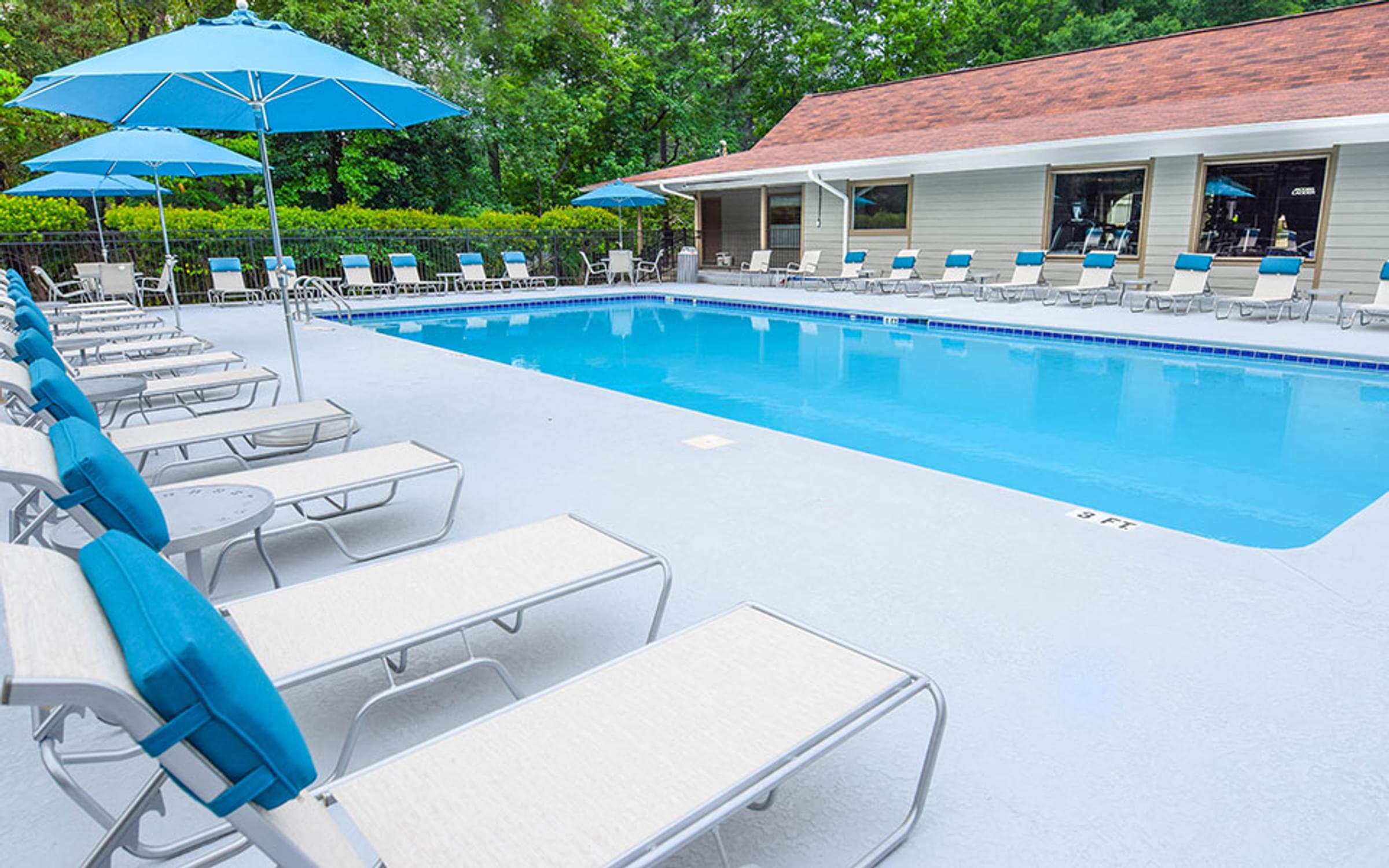 a pool with chairs and umbrellas next to a building