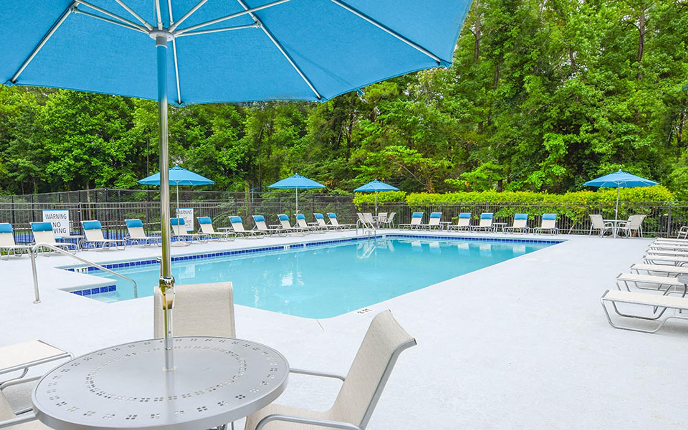 a swimming pool with a table and chairs under an umbrella