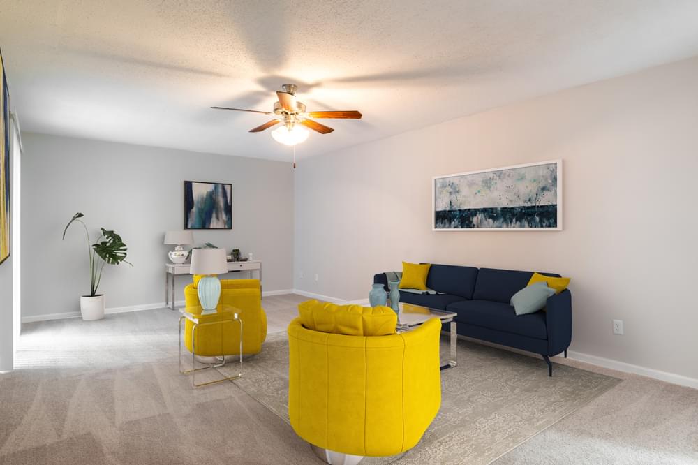 a living room with yellow furniture and a ceiling fan
