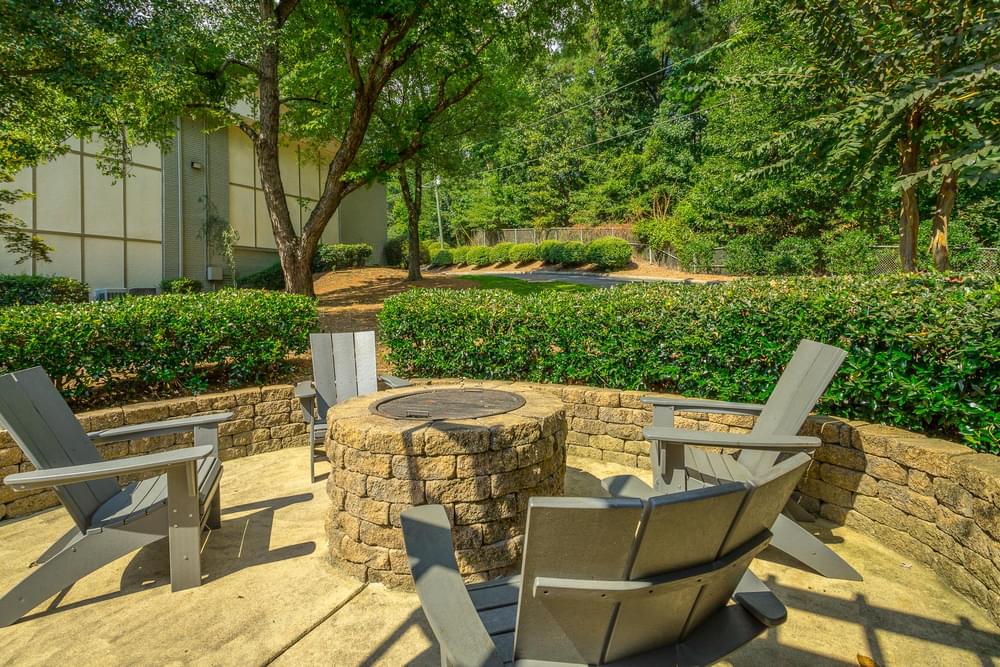 a stone patio with chairs and a fire pit