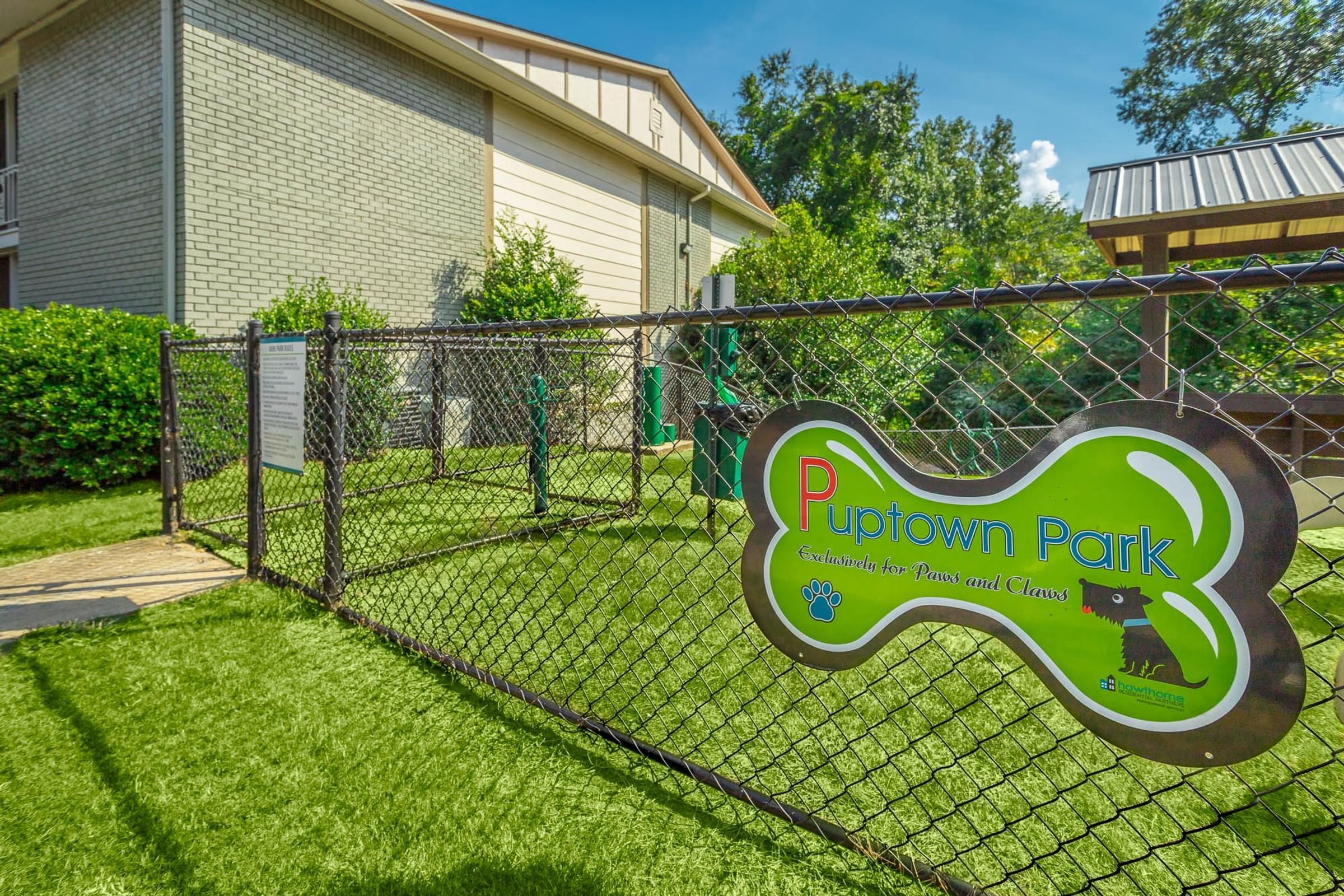 A sign for Puptown Park is displayed in front of a fence.