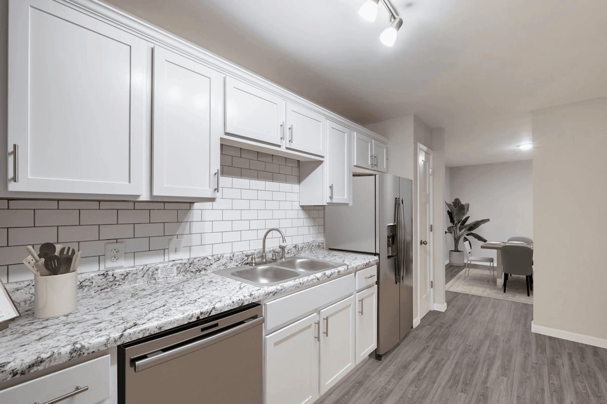 A kitchen with white cabinets and a marble countertop.