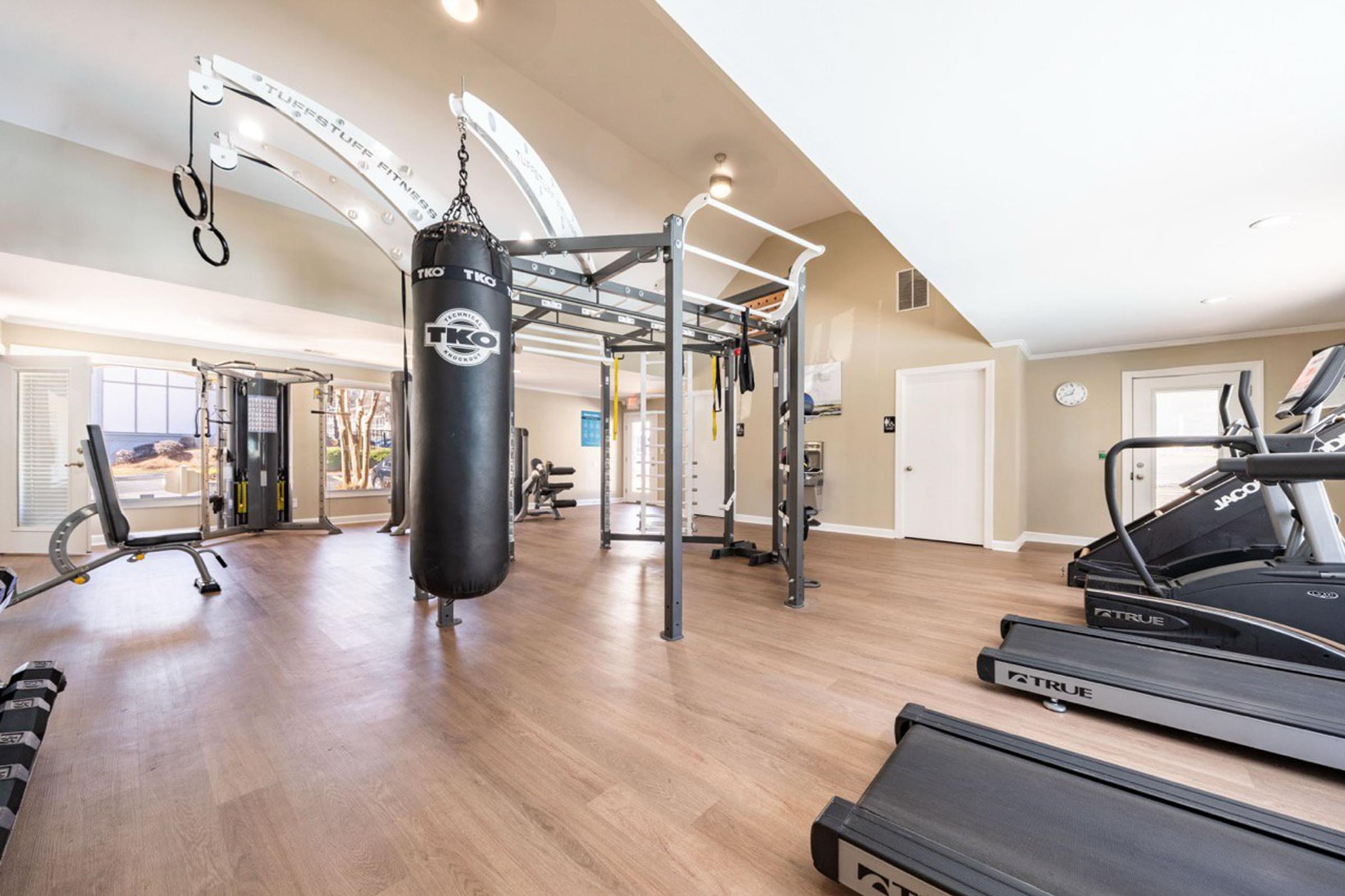 A gym with a punching bag, treadmills, and other exercise equipment.