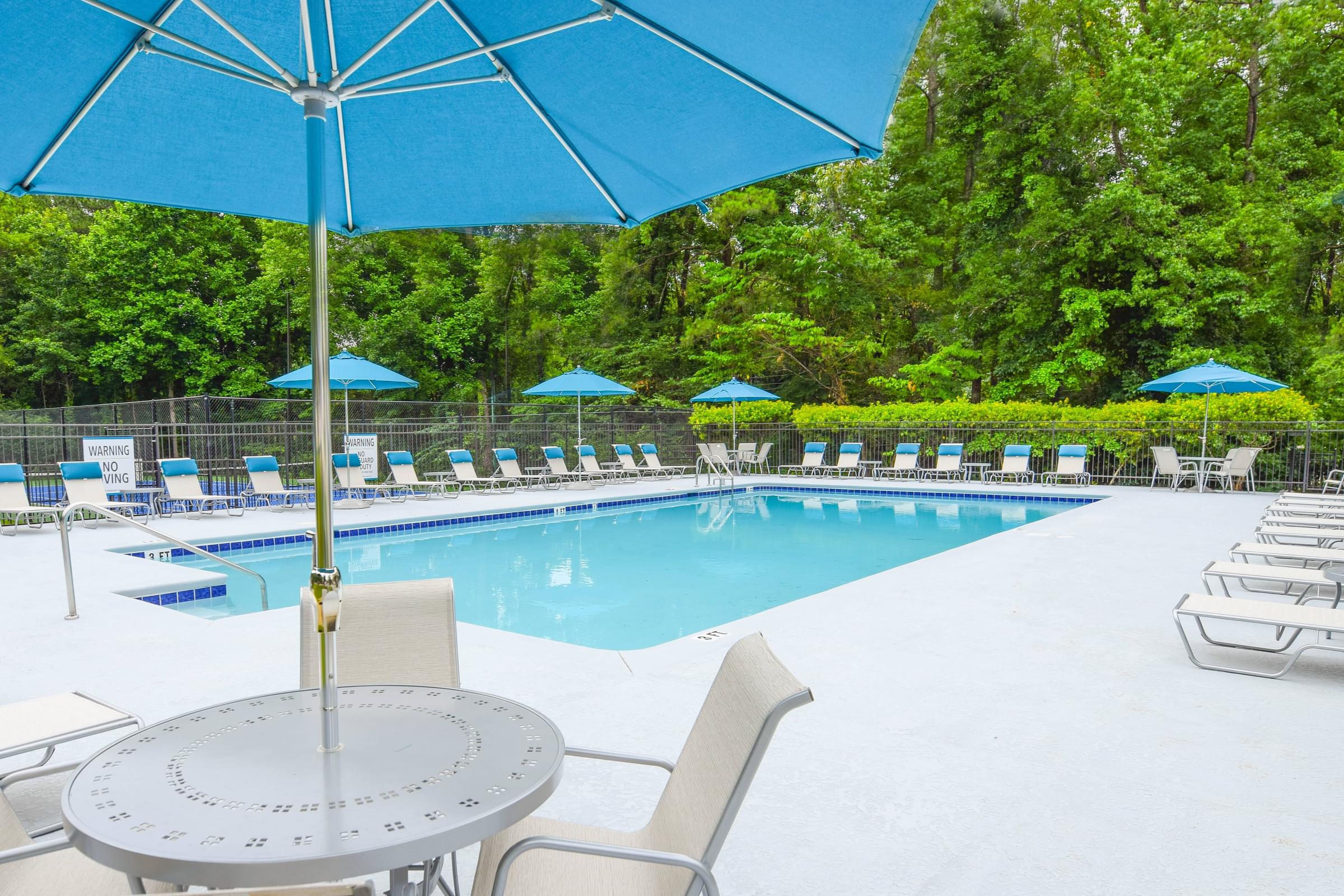 A pool with a table and chairs and umbrellas.