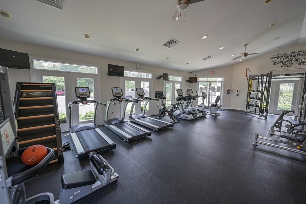 a gym with cardio equipment and windows in a building