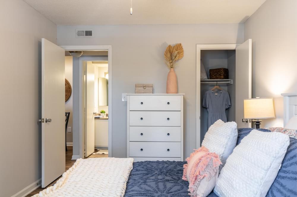 a bedroom with a bed and a dresser with a closet