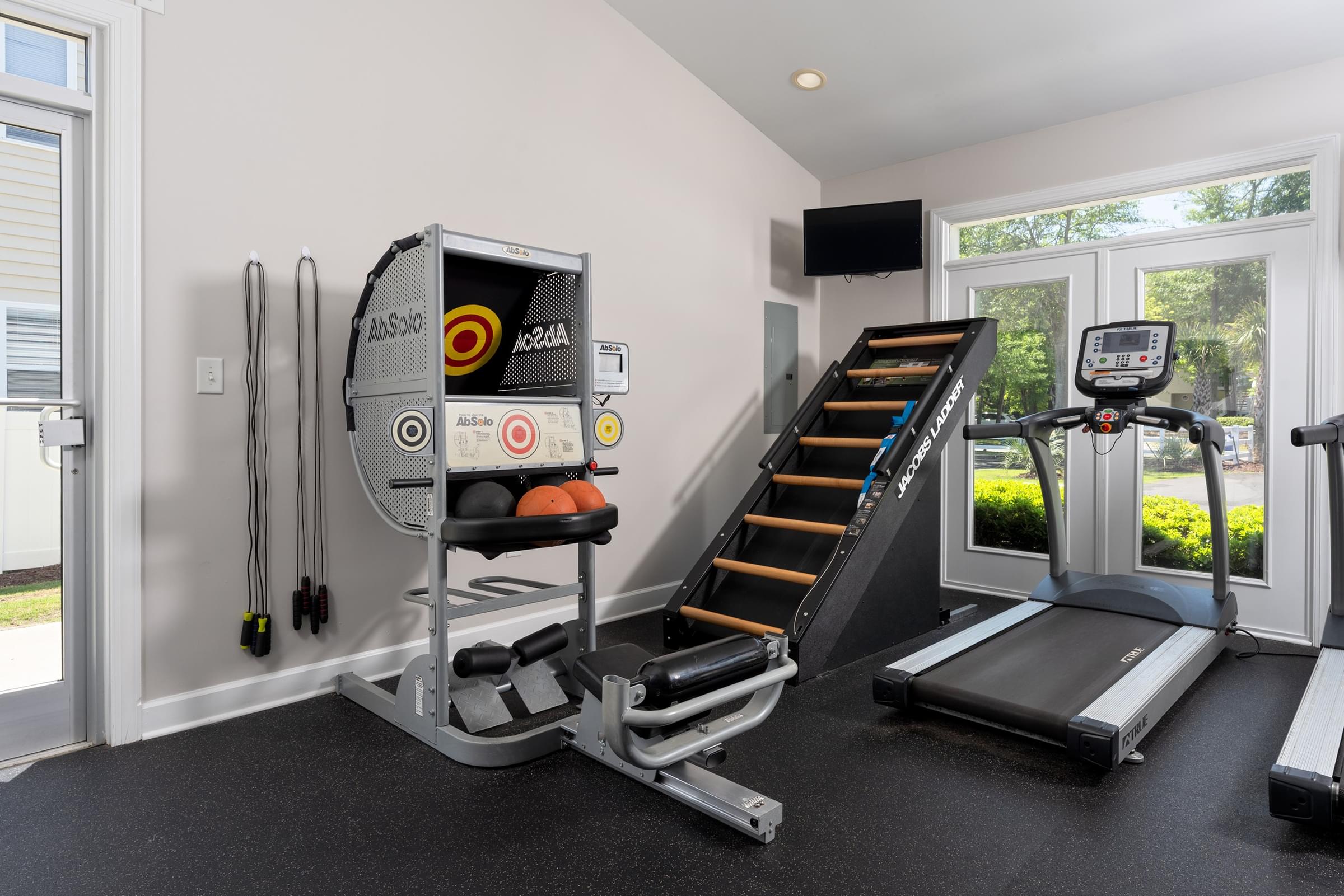 A home gym with a treadmill, a rowing machine, and a stair climber.