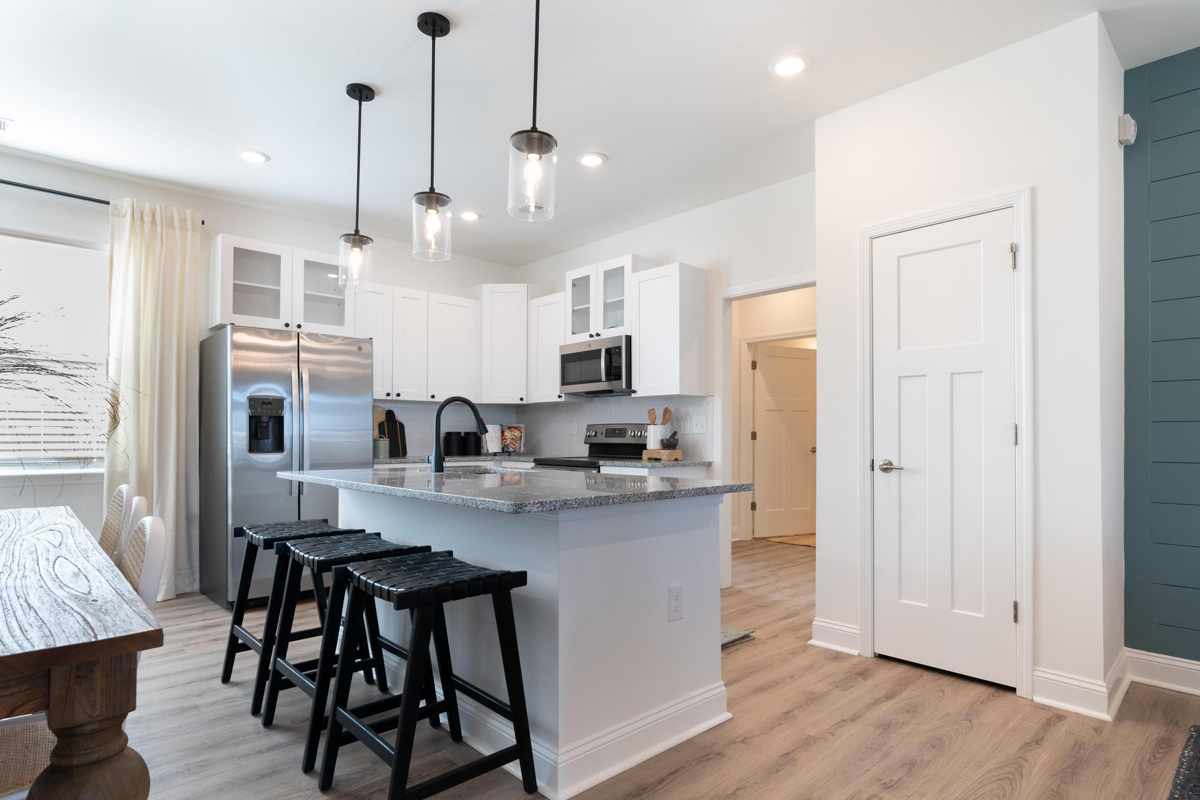 A kitchen with a white island and black bar stools.
