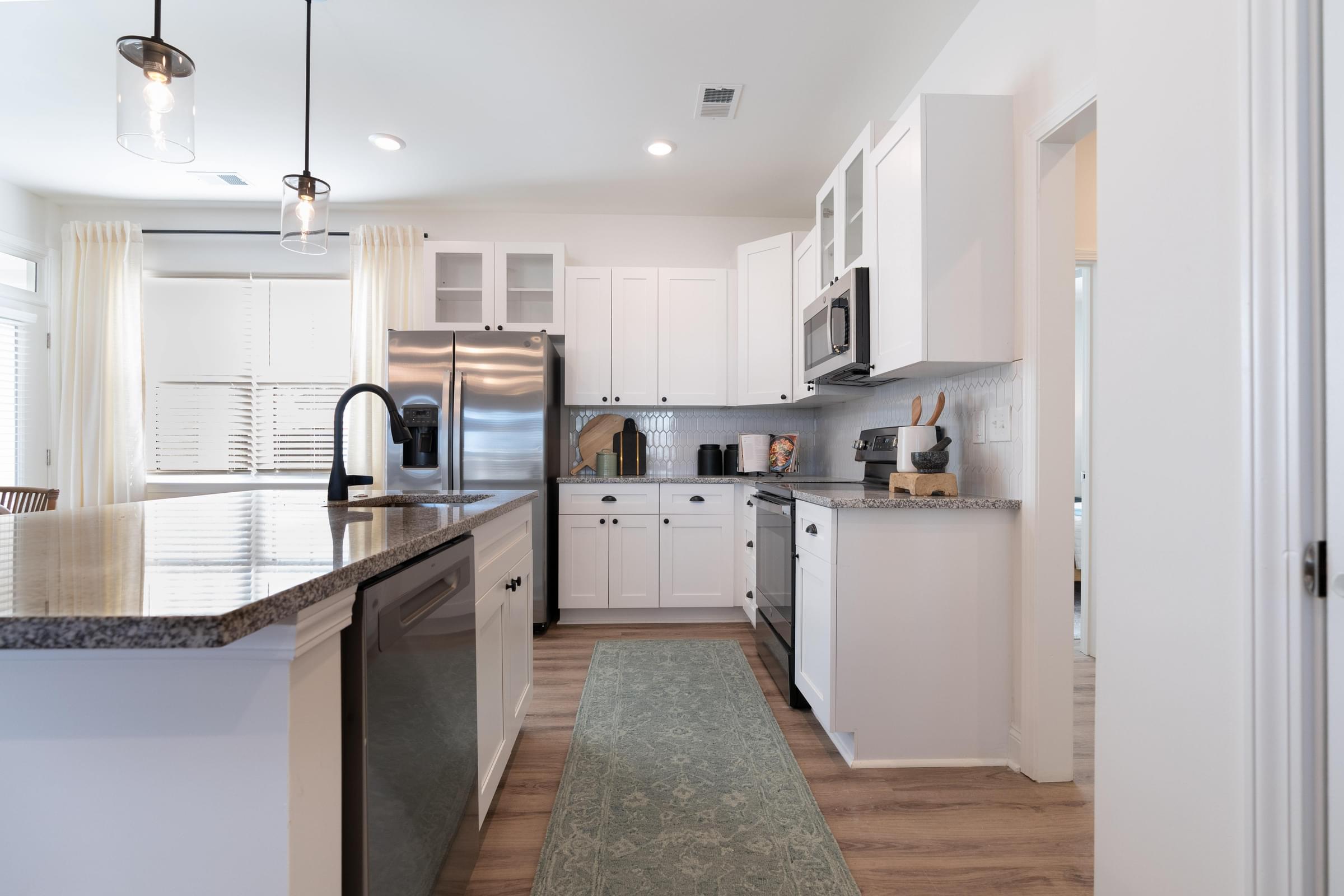 A kitchen with white cabinets and a granite countertop.