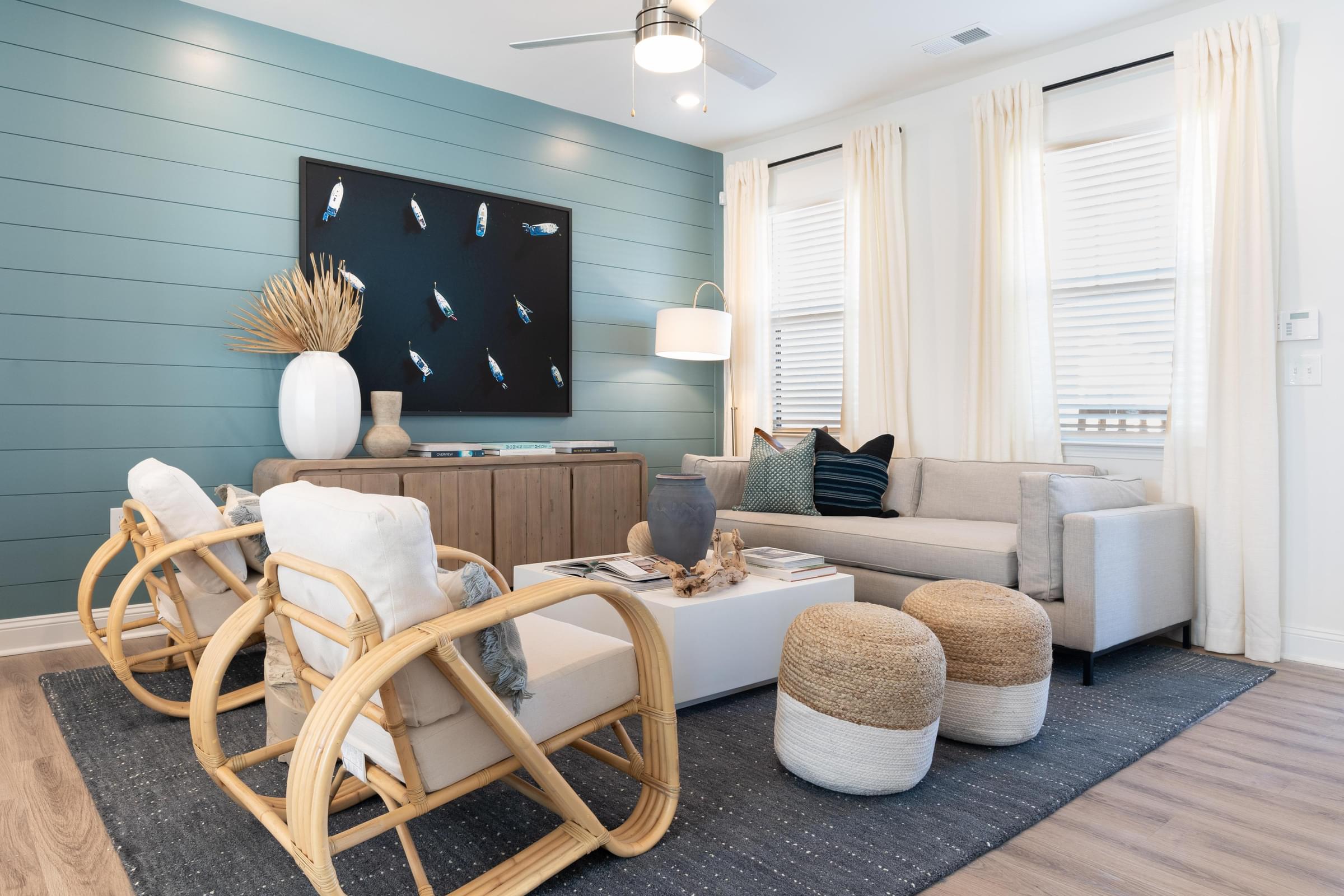A living room with a white sofa, a wooden rocking chair, and a large painting on the wall.