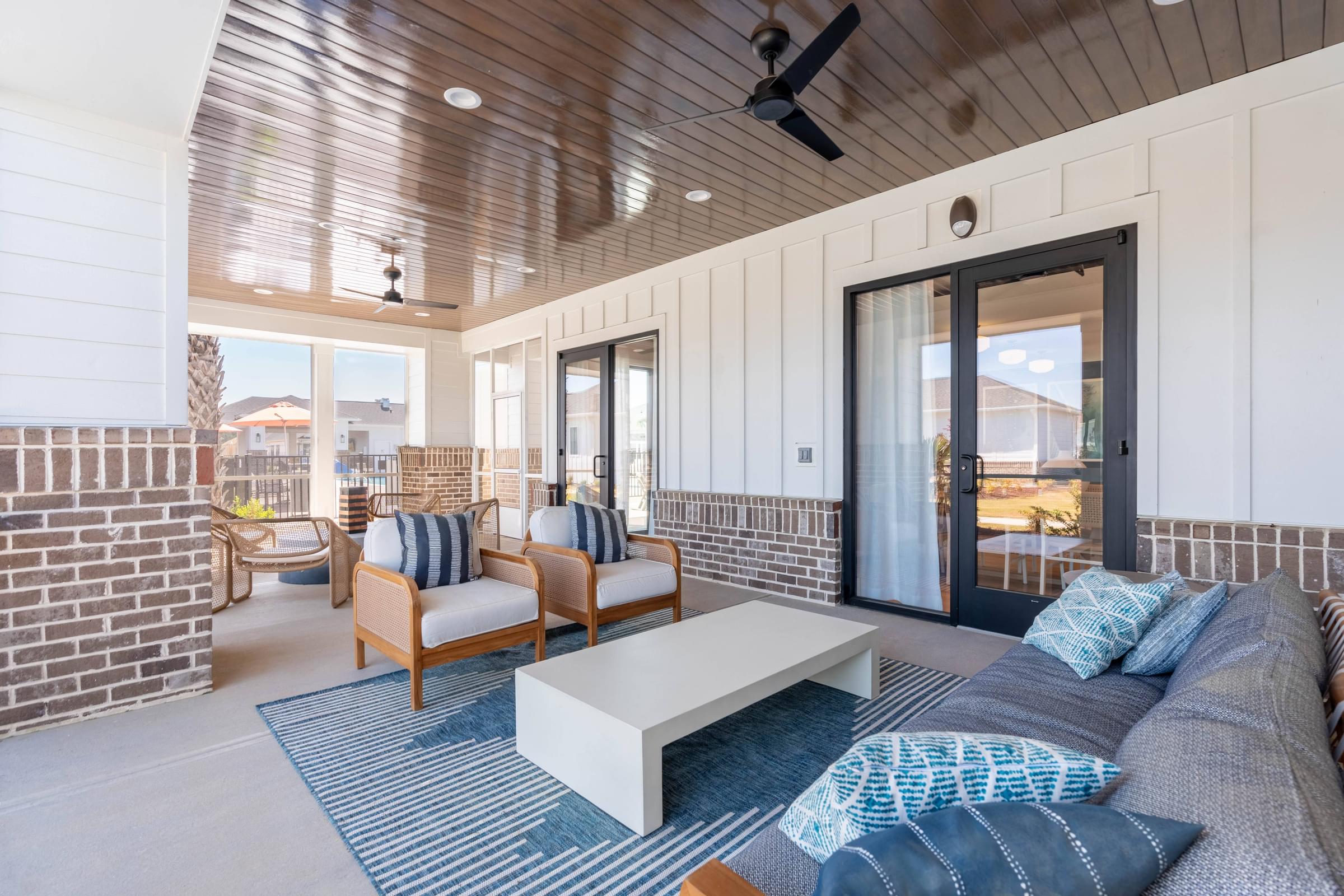 A modern outdoor living space with a wooden ceiling fan and furniture.